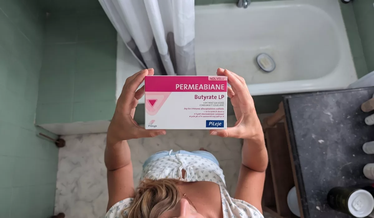Femme enceinte tenant une boîte de probiotiques au butyrate, dans le cadre d'un article sur la prévention de l'accouchement prématuré.
